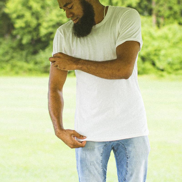 Man wearing a white Homesteader Fit M t-shirt, rolling up one of the sleeves.