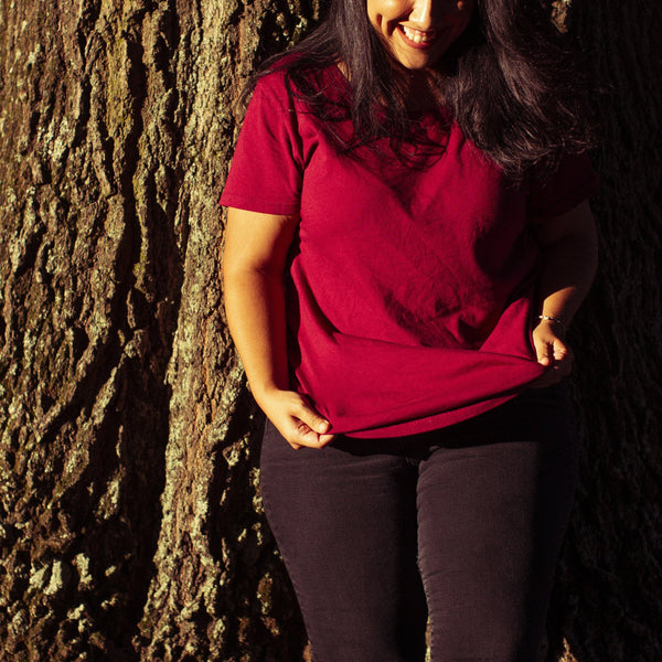 Woman leaning against a tree wearing the Solid State Clothing Homesteader Fit F t-shirt in red