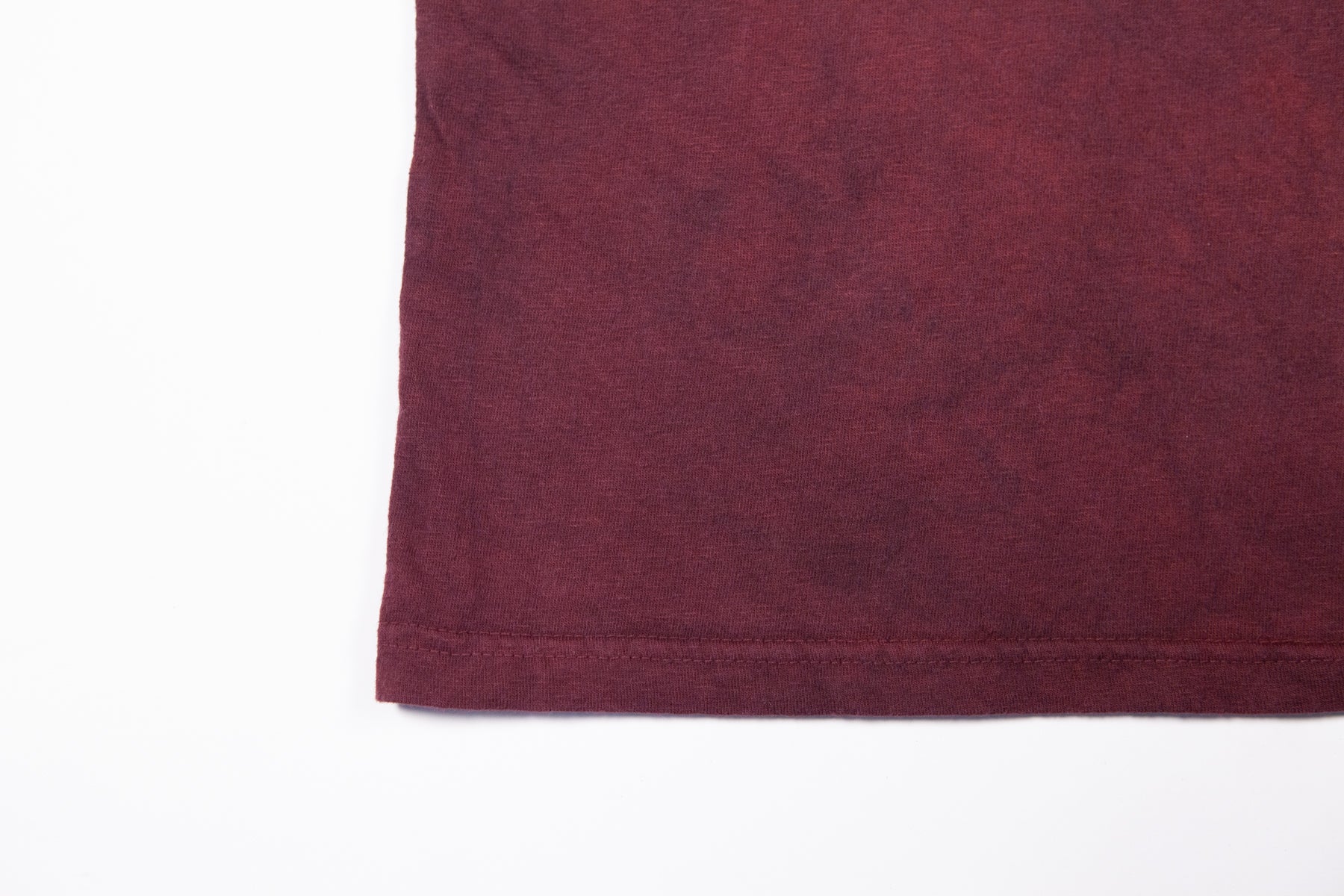 A close-up of crewneck t-shirt made in the USA and dyed with madder root standing laying flat on a white background