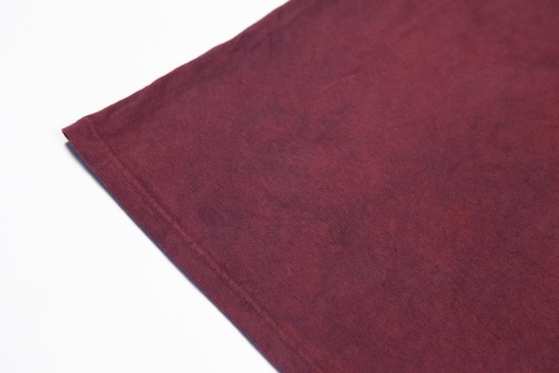 A close-up of crewneck t-shirt made in the USA and dyed with madder root standing laying flat on a white background