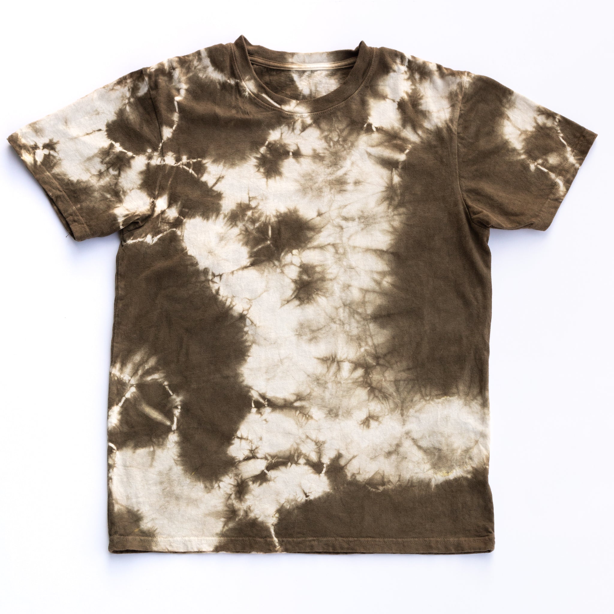 A Solid State Clothing Natural Tie Dye t-shirt lies against a plain background. Because each shirt is hand dyed in the USA, the pattern varies in all photos of shirts. The shirt pictured here has an even amount of green and white in its pattern
