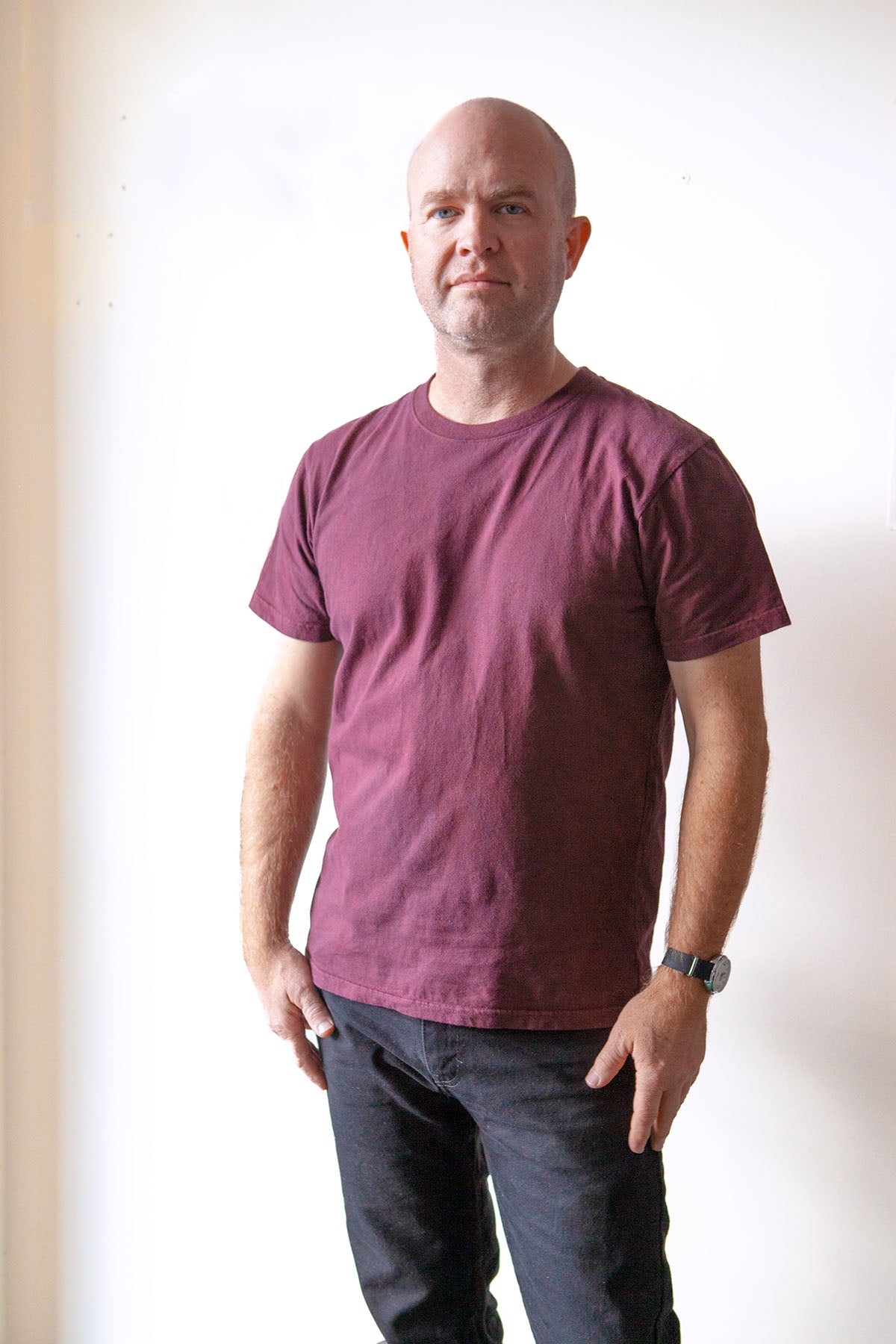 Man wearing a crewneck t-shirt made in the USA and dyed with madder root standing in front of a white wall