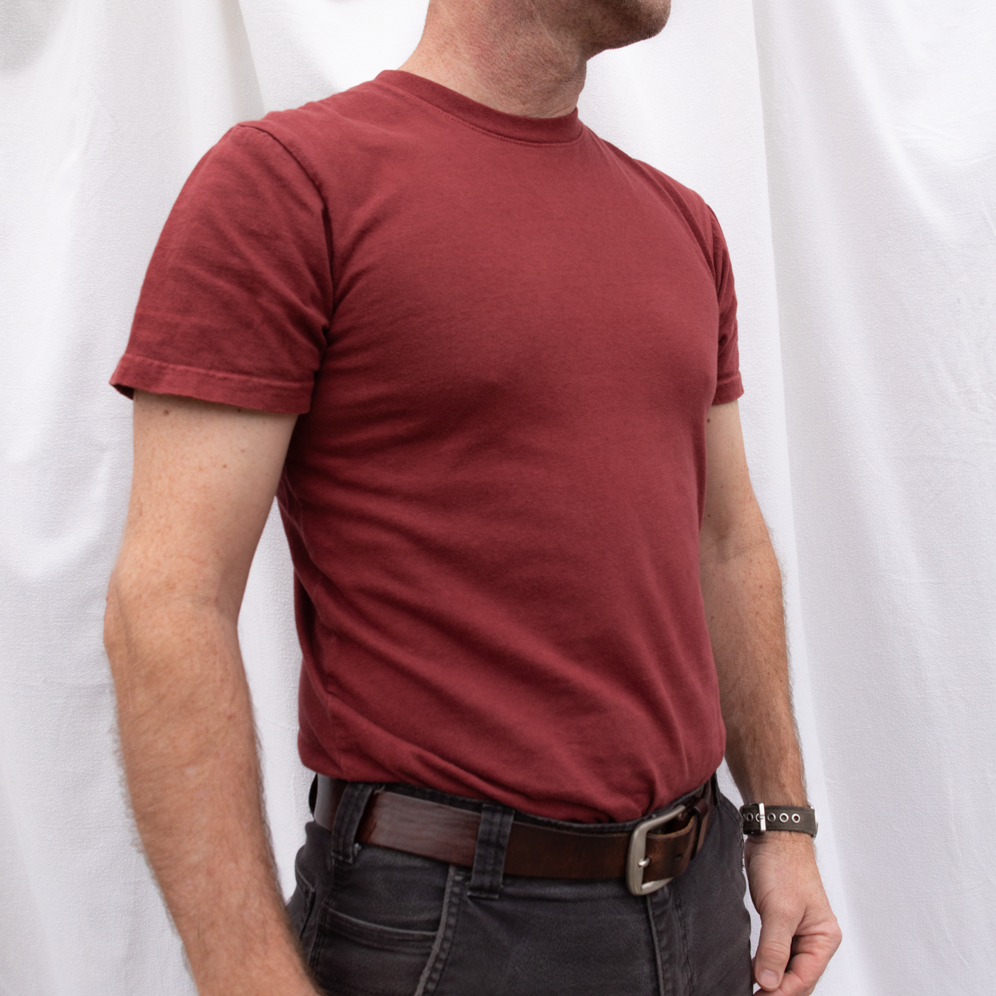 A close up photo of a man wearing an American-made Solid State Clothing Natural Dye t-shirt in Port