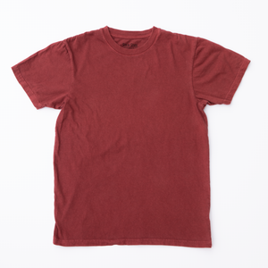 A Solid State Clothing Natural Dye t-shirt lies against a white background. The color of the shirt is Port, which is a darker, muted shade of red