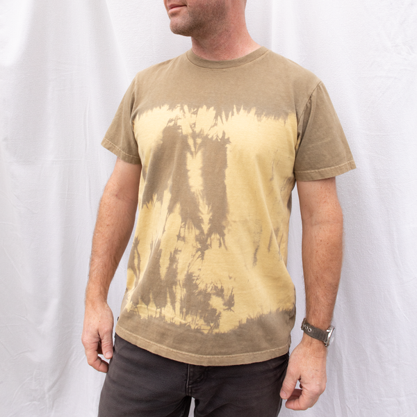 A close up photo of a man wearing an American-made Solid State Clothing t-shirt in natural tie dye color Riverbed.
